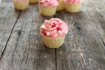 Pink cupcake dotted with little hearts on old wood board