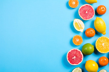 Several kinds of whole and cut citrus on a blue background