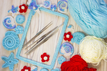 Marine background with cotton lace crochet craft elements: stars, shells, flowers and frame made of soft acrylic like wool yarn. Crocheted creative small doilies. Marine design