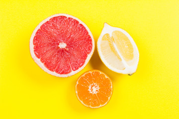 Several kinds of whole and cut citrus on a yellow background