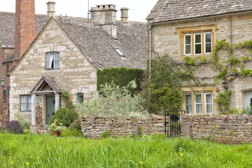 Traditional English honey golden brown stoned cottages in a rural village with walled front gardens, on a summer sunny day