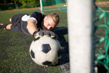 Naklejka premium goalkeeper with ball at football goal on field