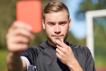 referee on football field showing red card