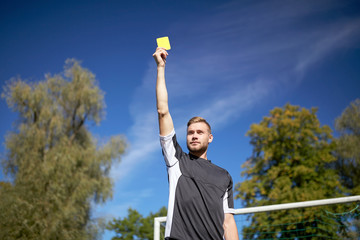 referee on football field showing yellow card