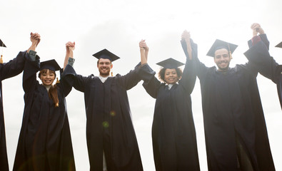 happy students or bachelors celebrating graduation