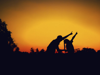 silhouette of mother and little daughter play at sunset