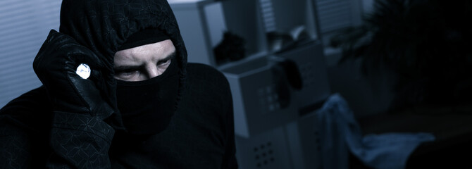 Masked burglar with flashlight