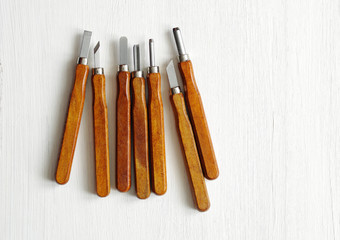 Graver chisels on a white wooden background. 