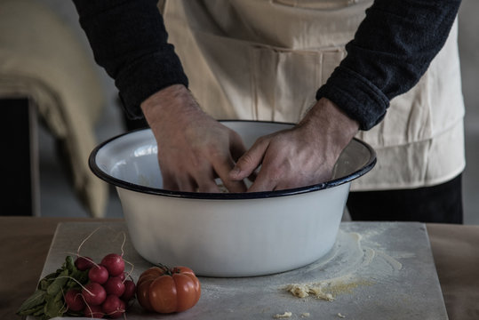 hands of a person kneading dough in a bowl on marble carving board on table
