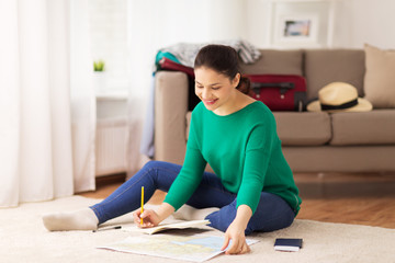 woman with notebook and travel map at home