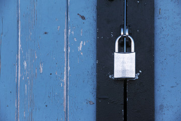 Silver padlock on an old blue wooden door, concept background