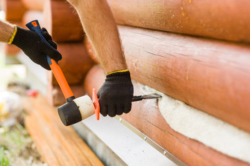 Male hands caulk log walls