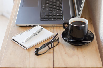 Workplace with a laptop, coffee, notebook and a glasses