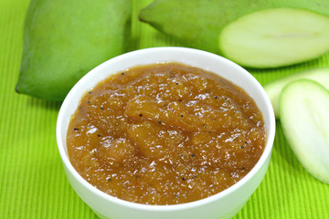 Mango chutney with green mangoes on the background.