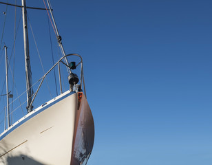 Bow of a white sailing yacht against the blue sky, generous copy space