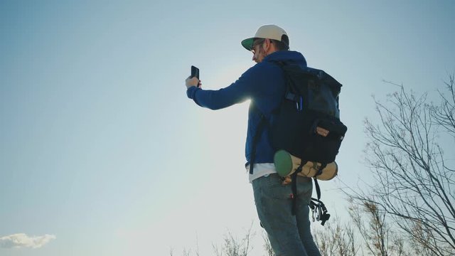 Man takes photo or selfie or streams video story online with his smartphone at bright sunny day, then walks away