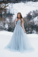 Fototapeta na wymiar Lady in a luxury lush blue dress, fantastic shot, fairytale princess is walking in the winter forest