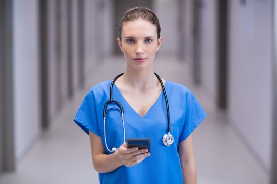 Portrait of female doctor using mobile phone in corridor