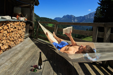 Mann liest in der Hängematte im Gebirge