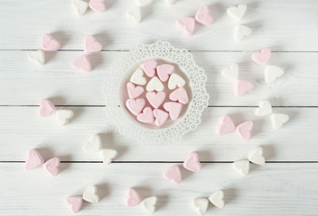 white wooden background of pink and white marshmallow hearts. 