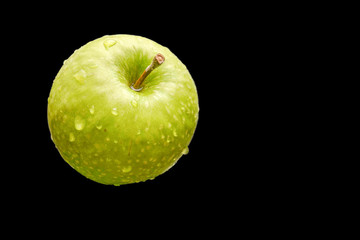 Grüner Apfel mit Wassertopfen auf schwarzem Hintergrund