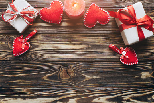 Wooden background with hearts, candles and gifts on Valentine day. Romantic atmosphere