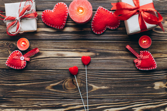 Wooden background with hearts, candles and gifts on Valentine day. Romantic atmosphere