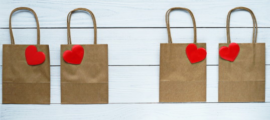 gift bags with red heart symbol of love on a white wooden background