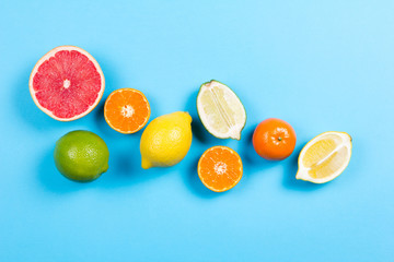 Several kinds of whole and cut citrus on a blue background