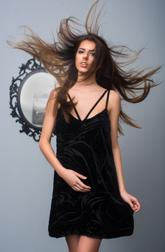 Beautiful sexy woman posing in a  little black dress. Model with flying hair. Shooting lookbook. Collection Spring 2017. Fashion shooting for catalog. fashion trend spring-summer 2017