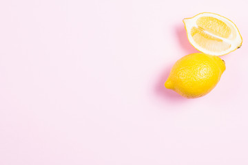 Whole and sliced lemon on pink background