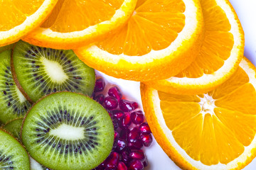 Healthy food for active life, fruits. Sliced oranges and kiwi, pomegranate seed. Orange slices arranged on a circle. White background.