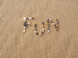 Fototapeta na wymiar word fun written with stones and shells on the beach by the ocean
