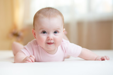 Cute baby wearing lying on tummy in bedroom