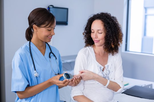 Doctor examining pregnant woman's blood sugar