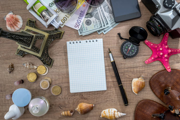 travel concept - old camera, empty notebook with pencil, euro bills, compass, seashell, phone.