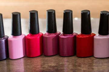 Group of bright nail polishes on wooden desk.