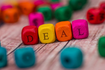 deal - word created with colored wooden cubes on desk.