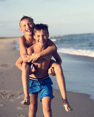 Portrait of two happy kids playing on the beach on summer vacat