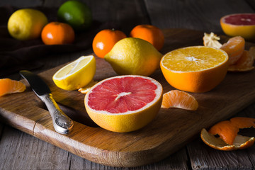 various types of citrus fruit on a dark wooden background