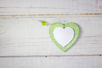 Two wooden hearts - white and green over the wooden background