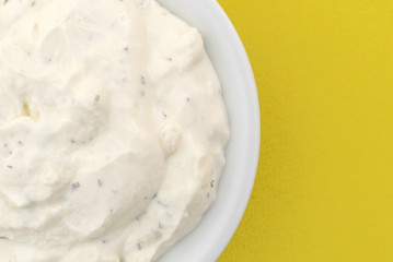 Top close view of a small bowl of French onion dip on yellow tablecloth.