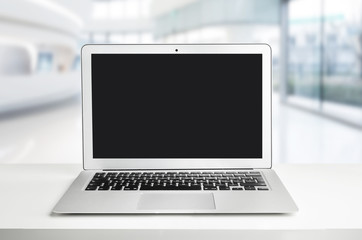Fototapeta premium Laptop with black screen on a white table in office.
