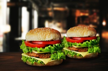 Two fresh tasty burgers with vegetables on wooden table in resta