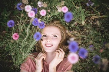 Fototapeta premium The girl dremet among wildflowers in evening. Edit in dark atmosphere, muted colors, high contrast, selective focus, low depth of field.