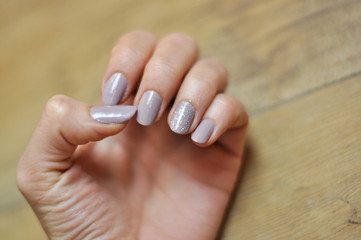 Woman's hand with manicure on wooden board