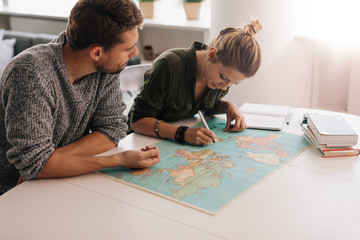 Young couple exploring the world map.