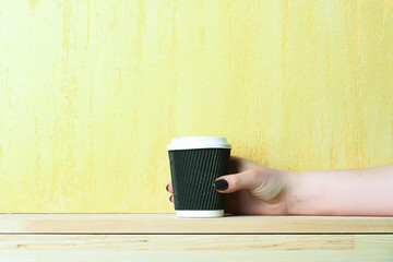 paper or plastic coffee cup in hand on textured background