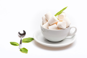 cup with marshmallow on plate with spoon and basil