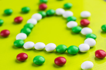 Candies in the shape of heart on yellow background